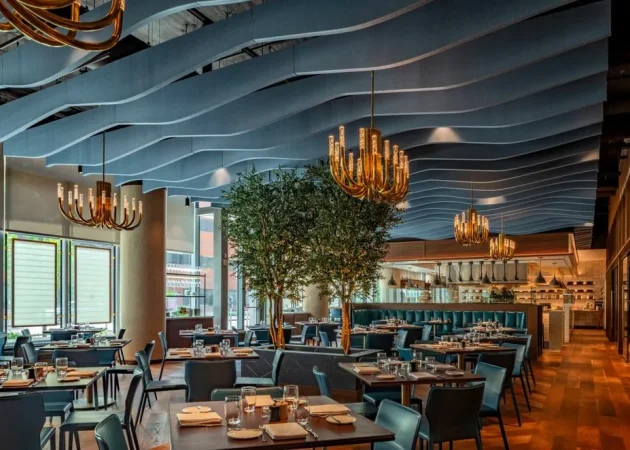 Interior view of a modern restaurant featuring decorative chandeliers and a faux olive tree.