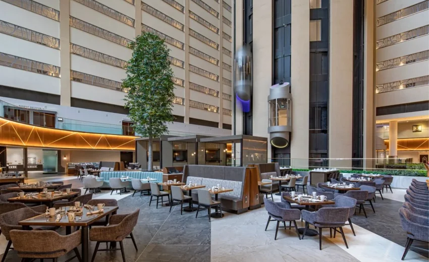 Interior view of a modern restaurant featuring seating areas and a tall indoor tree.
