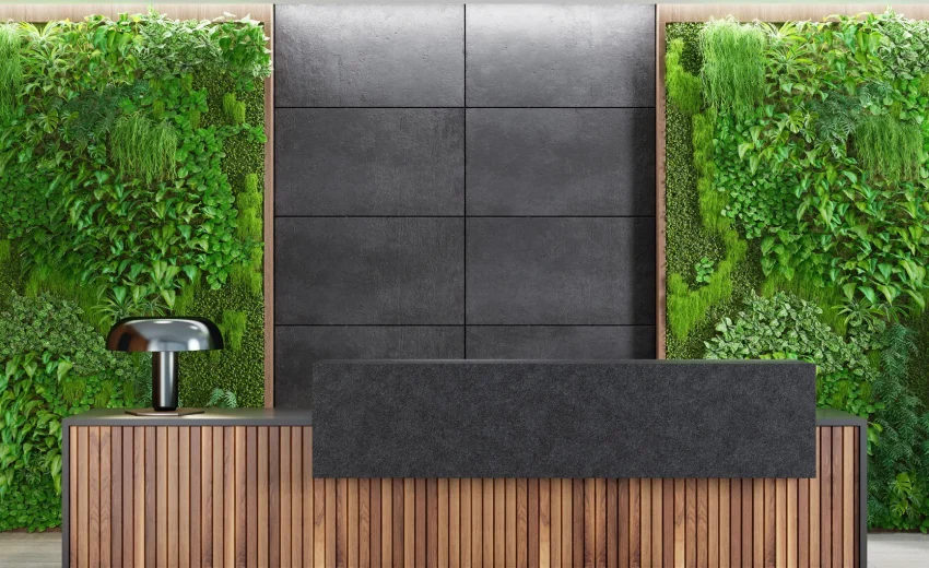 Reception desk made of wood with a dark gray panel and green wall behind it.
