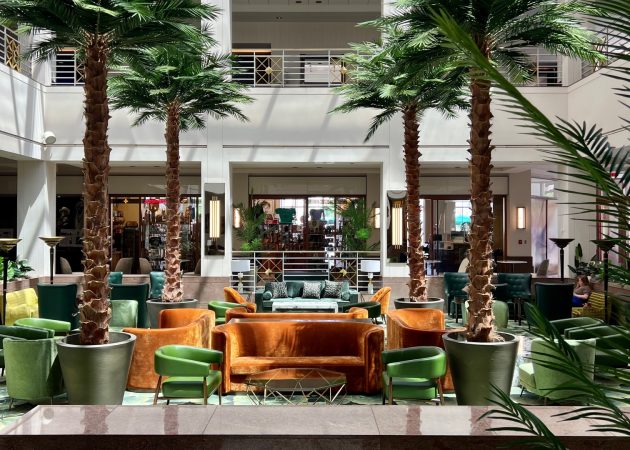 Indoor seating area featuring palm trees and various seating arrangements in a hotel lobby.