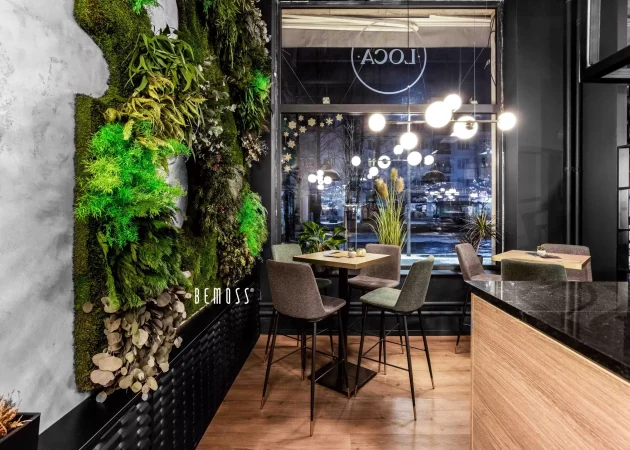 Indoor seating area featuring a greenery wall and modern furniture in a restaurant setting.