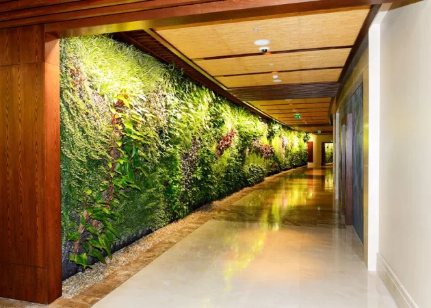 Faux green wall featuring various plants in a hotel corridor with polished flooring.