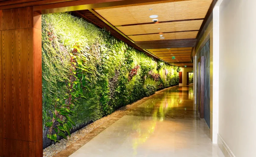 Faux green wall featuring various plants in a hotel corridor with polished flooring.
