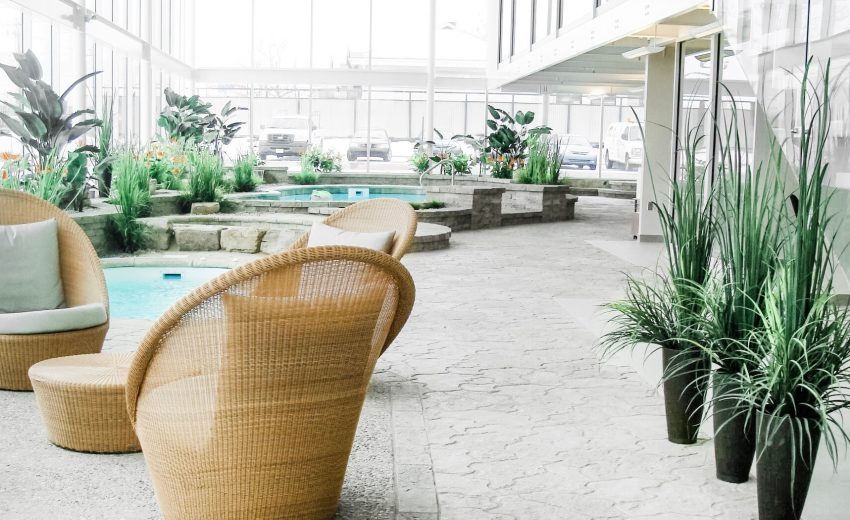 Indoor relaxation area featuring wicker chairs, plants, and a pool, designed for comfort and tranquility in a modern setting.