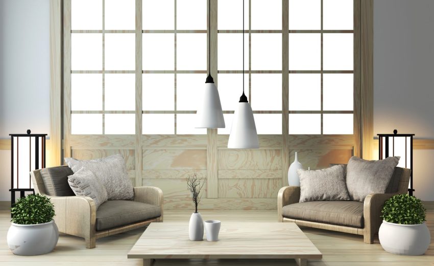 A modern living room featuring two sofas, decorative pillows, hanging lights, and potted plants, creating a cozy atmosphere.