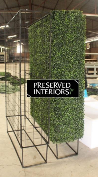 A custom faux boxwood hedge structure with a metal frame, designed for display purposes.