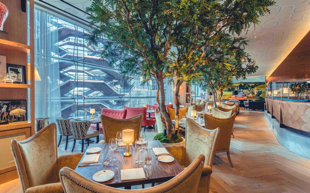 Interior of a modern restaurant featuring elegant seating, decorative trees, and a stylish ambiance, ideal for dining experiences.