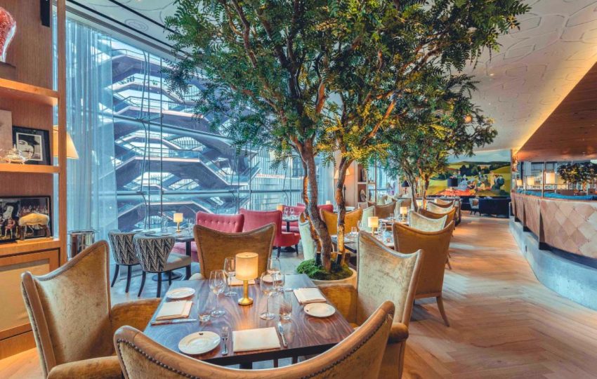 Interior of a modern restaurant featuring elegant seating, decorative trees, and a stylish ambiance, ideal for dining experiences.