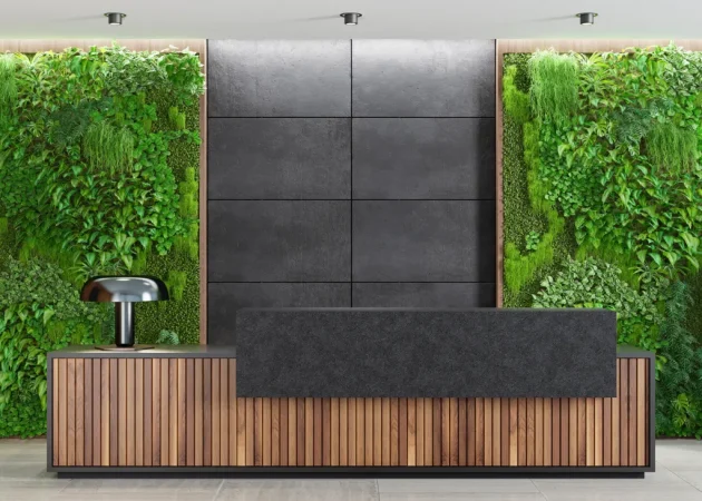 Modern reception desk with a wooden front and a green living wall behind it.