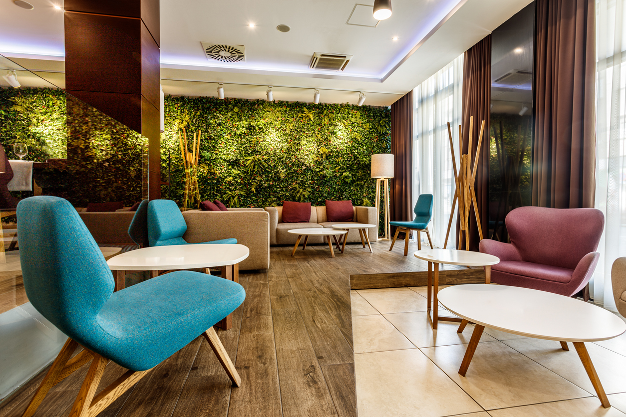 Seating area in a lobby featuring a faux green wall and various chairs and tables.