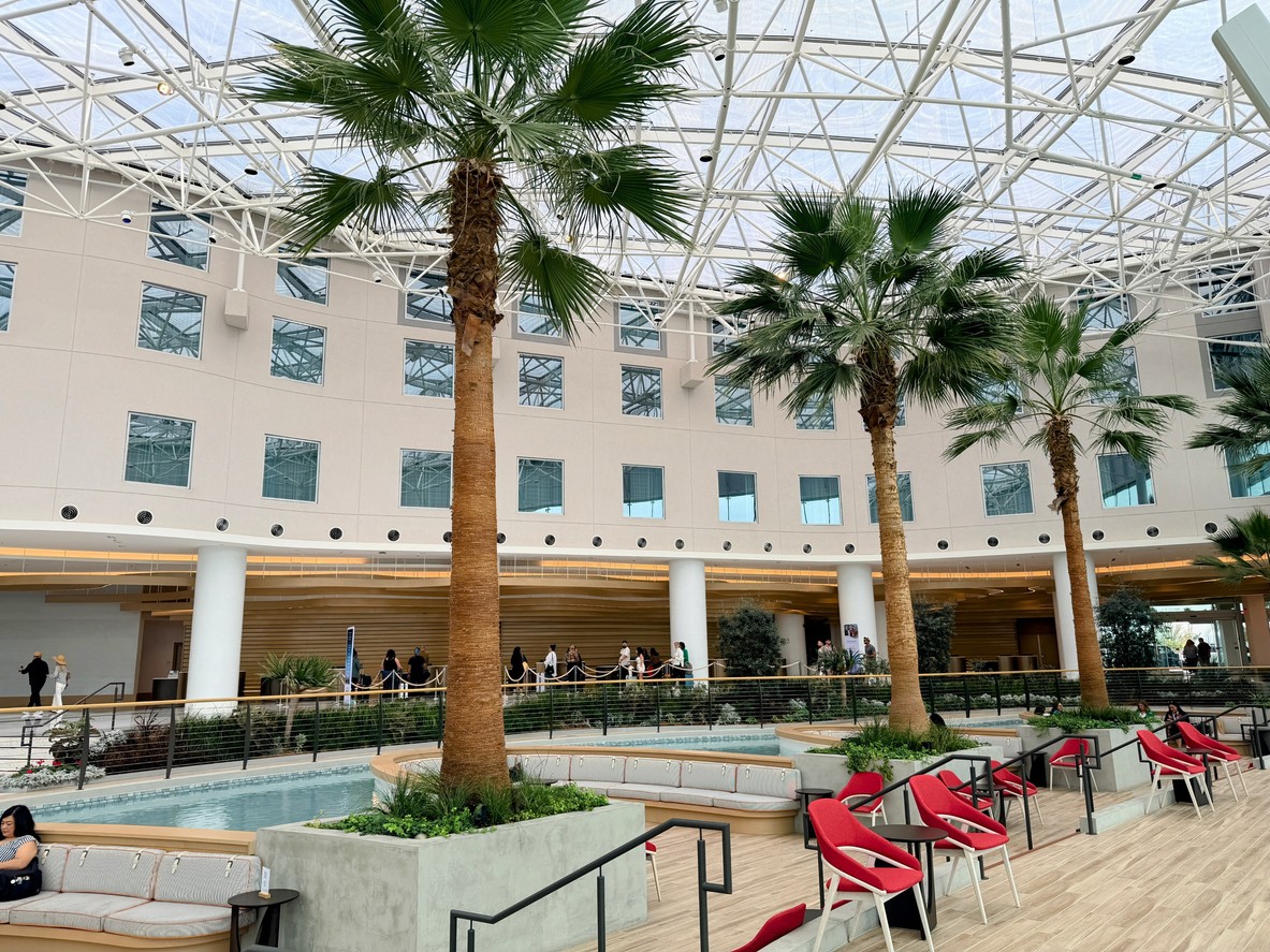 Indoor area featuring palm trees and modern seating arrangements in a well-lit environment.