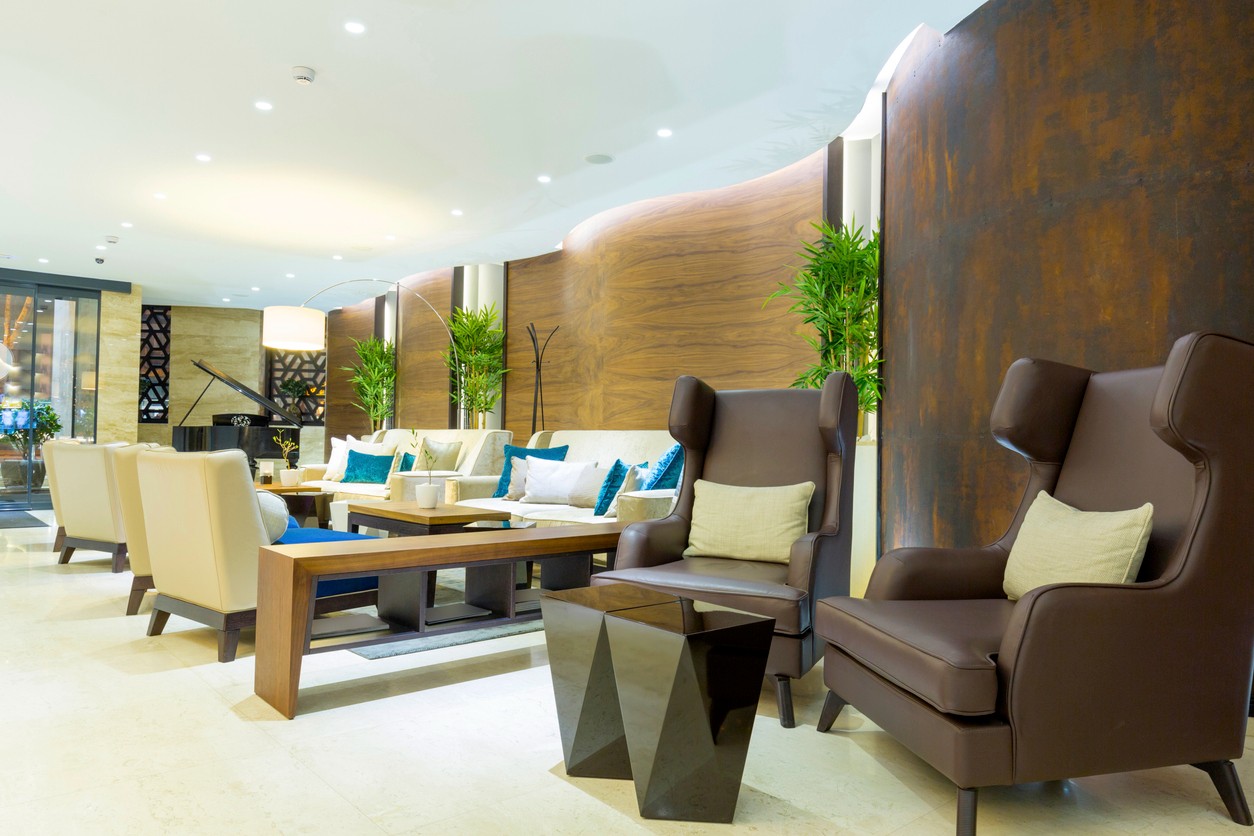 Contemporary lounge area featuring brown and beige seating, wooden accents, and decorative plants.