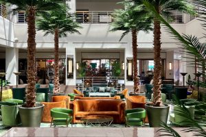 Indoor seating area featuring palm trees and various seating arrangements in a hotel lobby.