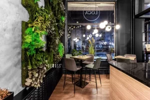 Indoor seating area featuring a greenery wall and modern furniture in a restaurant setting.