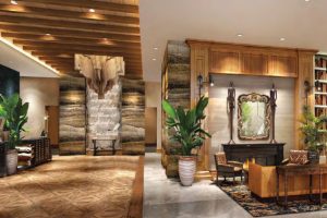 Interior view of a modern lobby featuring wood accents, plants, and a decorative fireplace.