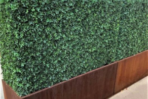 Custom faux boxwood hedge in a rectangular planter with a metal base.