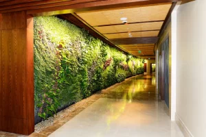 Faux green wall featuring various plants in a hotel corridor with polished flooring.